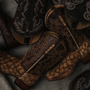 Pair of brown leather cowboy boots with intricate stitching on a concrete surface
