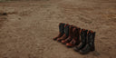 Set of cowboy boots arranged on a sandy surface
