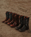 Set of cowboy boots arranged on a sandy surface